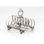 An early Victorian silver toast rack by G.I, with six spaces, handle with engraved family crest,