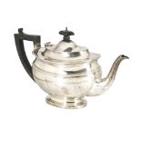 A George V silver teapot from C.S. Harris & Sons Ltd, oval on spreading foot, with applied black