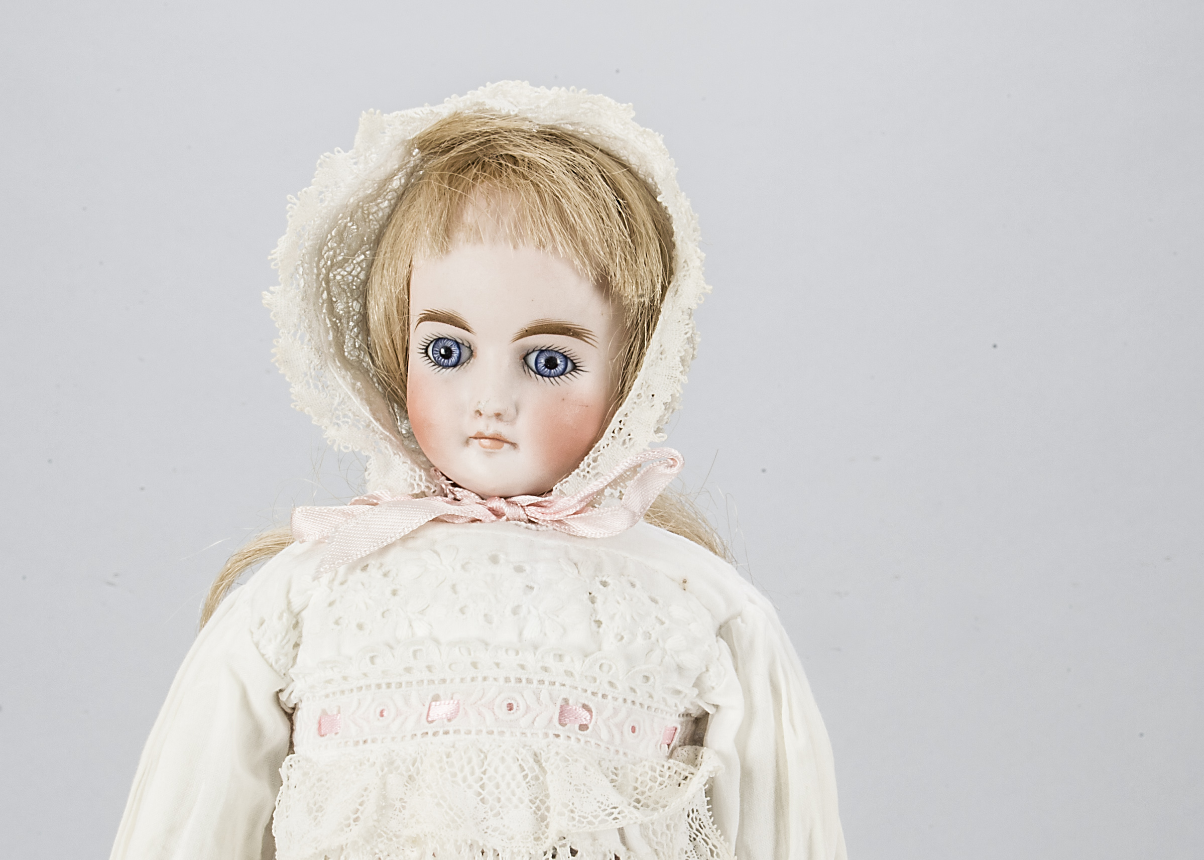 A German shoulder head doll, with fixed blue glass eyes, closed mouth, solid domed pate, turned