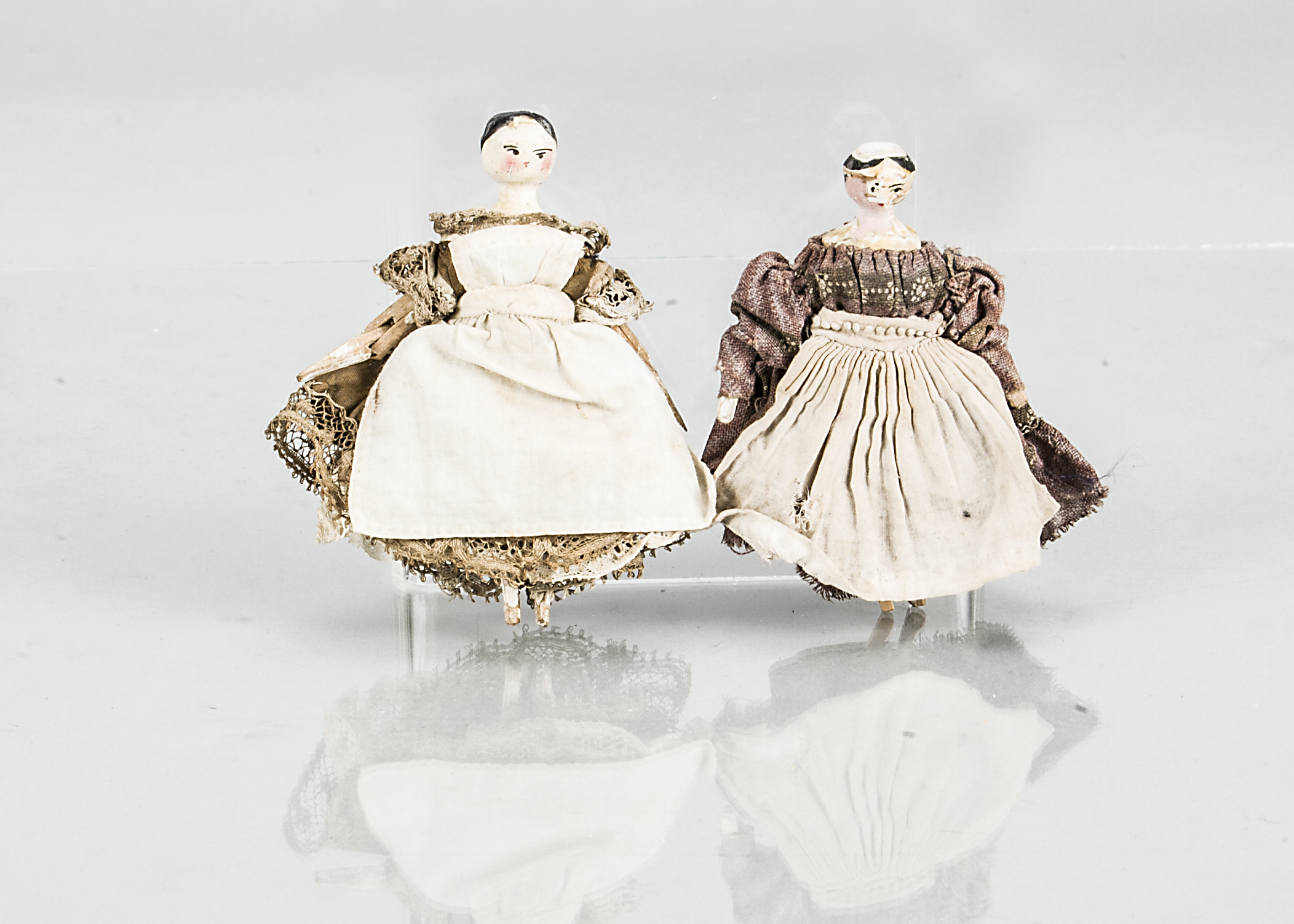 Two peg wooden/Grodnerthal dolls’ house dolls, with black painted smooth headed centre-parted