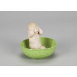 A Gebruder Heubach bathing girl, kneeling with hands washing hair in large green glazed basin and