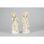 A pair of Gebruder Heubach seated seaside figures, the boy holding a fishing net and Sou'wester hat,