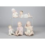 Five German bisque babies, a pair seated, one holding a pocket watch —7in. (18cm.) high, two other