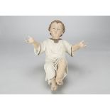 A plaster baby Jesus creche figure, lying with hands held upwards, hand painted with blue eyes and