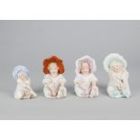 Four Gebruder Heubach seated girls in bonnets, two removing her socks —5in. (12.5cm.) high; and