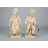 A pair of Gebruder Heubach figures of children playing, the boy with hoop and stick, the girl