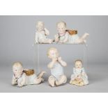 Five German bisque babies, a pair lying with basket posy vases on their backs —8½in. (21.5cm.) long,