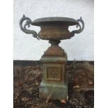 A cast iron twin handled garden urn, on a square pedestal base, 58cm x 100cm