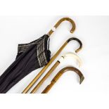 Three 20th Century wooden walking sticks, one with a bone handle, together with a black umbrella