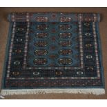 A 20th Century Bokhara rug, the central panel set with repeating medallions on a blue ground, within