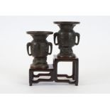 Two Meiji period bronze vases, of twin handled flaring shape, rising from the base above