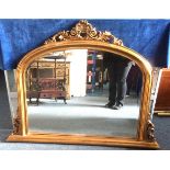 A contemporary gilded over mantle mirror, with scroll decoration and bevelled plate, 119cm x 92cm