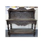 An antique oak buffet, with a carved panel back, serpentine shelf, swept carved frieze with an