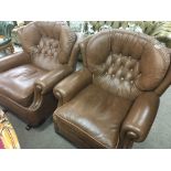 A pair of modern brown leather rocking arm chairs.