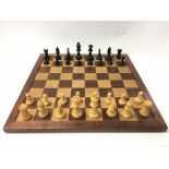 A carved wooden chess set with wooden chess board
