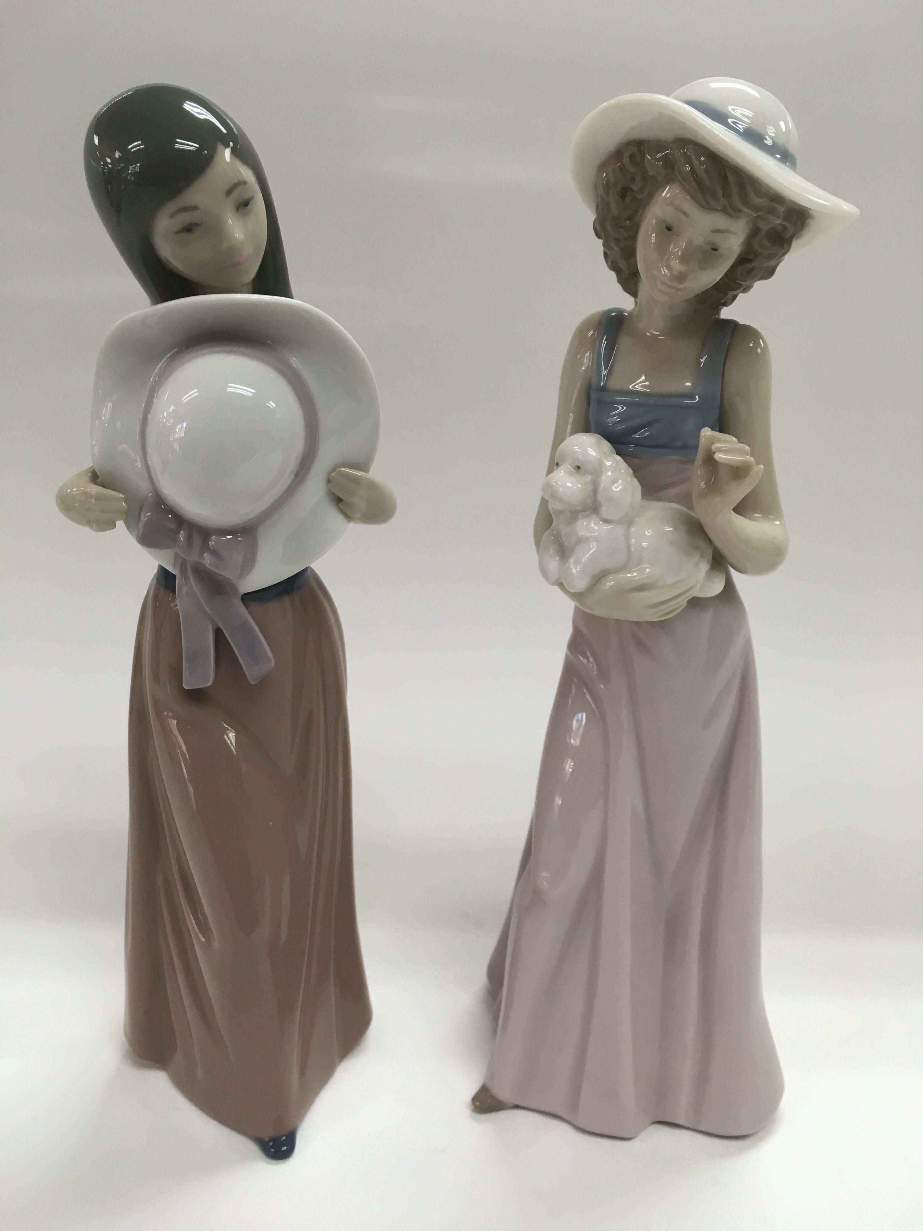 A Lladro figure of a girl holding a wide brimmed h