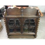 A turned wood wall display cabinet with glazed fro