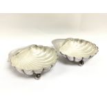 A pair of silver shell dishes with glass inserts.