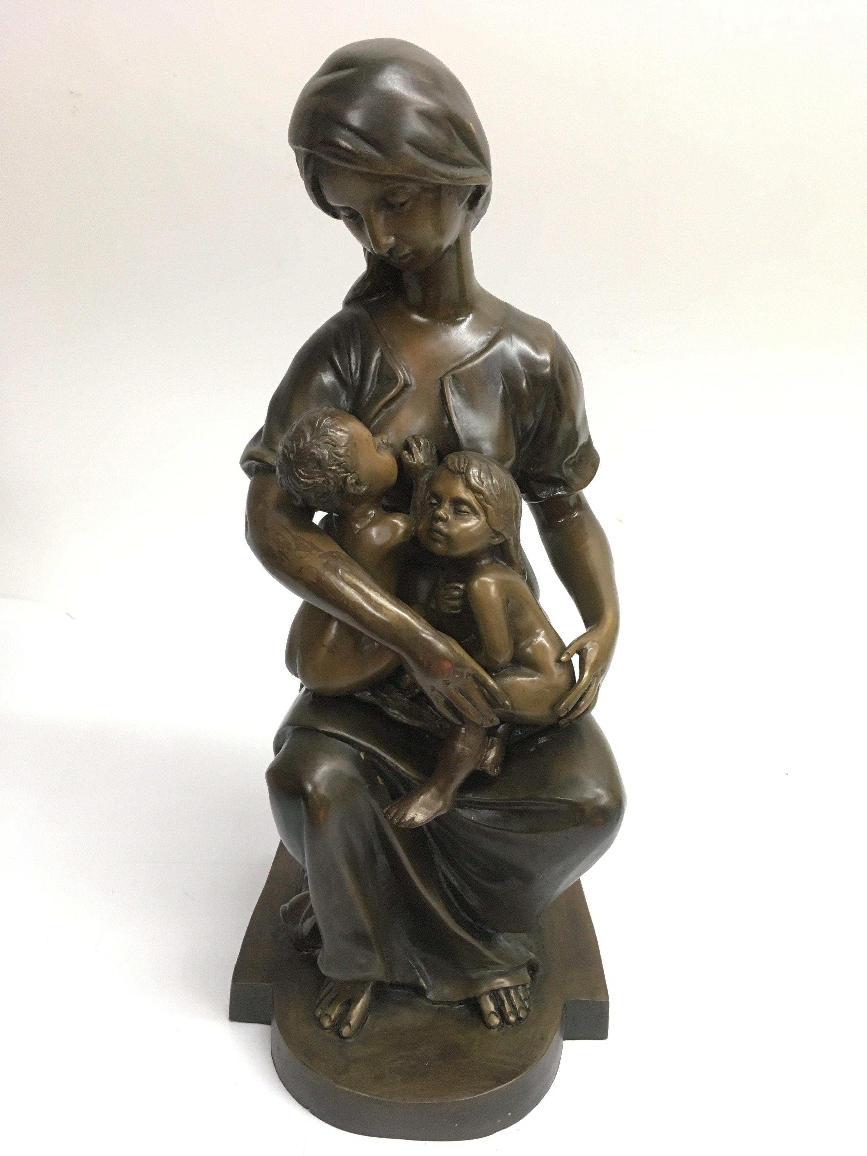 A contemporary cast metal figure of a woman holdin