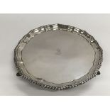 A silver tray with shaped edging and raised on thr