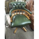 A green leather upholstered office chair with button back, turned supports.