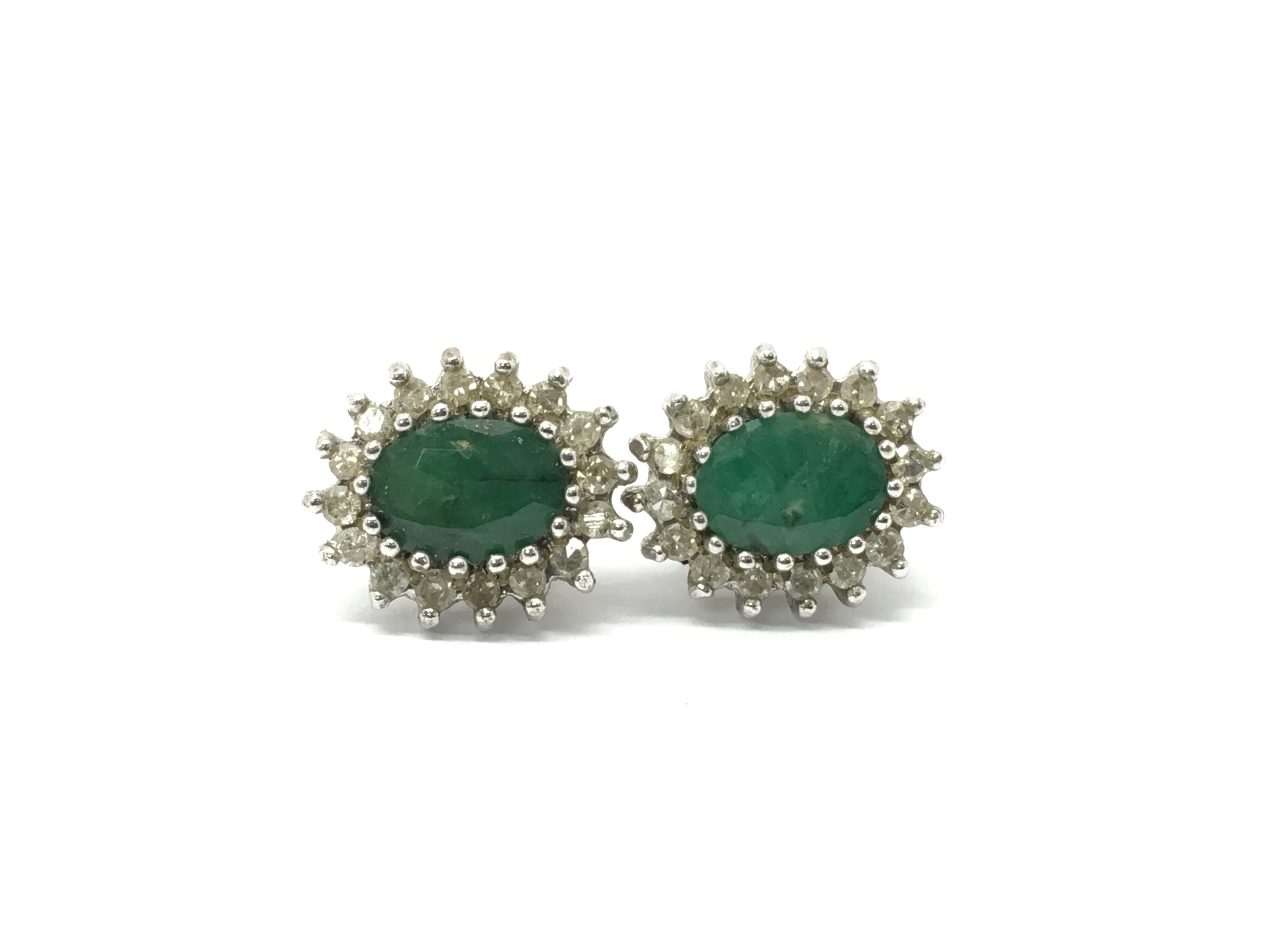 A pair of gold earrings set with a central emerald