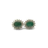 A pair of gold earrings set with a central emerald