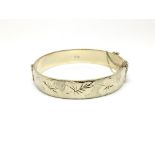 A silver bangle decorated with leaves, hallmarked