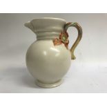 A Clarice cliff jug with foilage handle on a cream