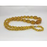 A citrine coloured bead necklace with yellow metal clasp.