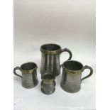 Four antique pewter and brass rimmed measuring tan