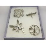 Four silver brooches, one of a fairy, one of a dragonfly and others.