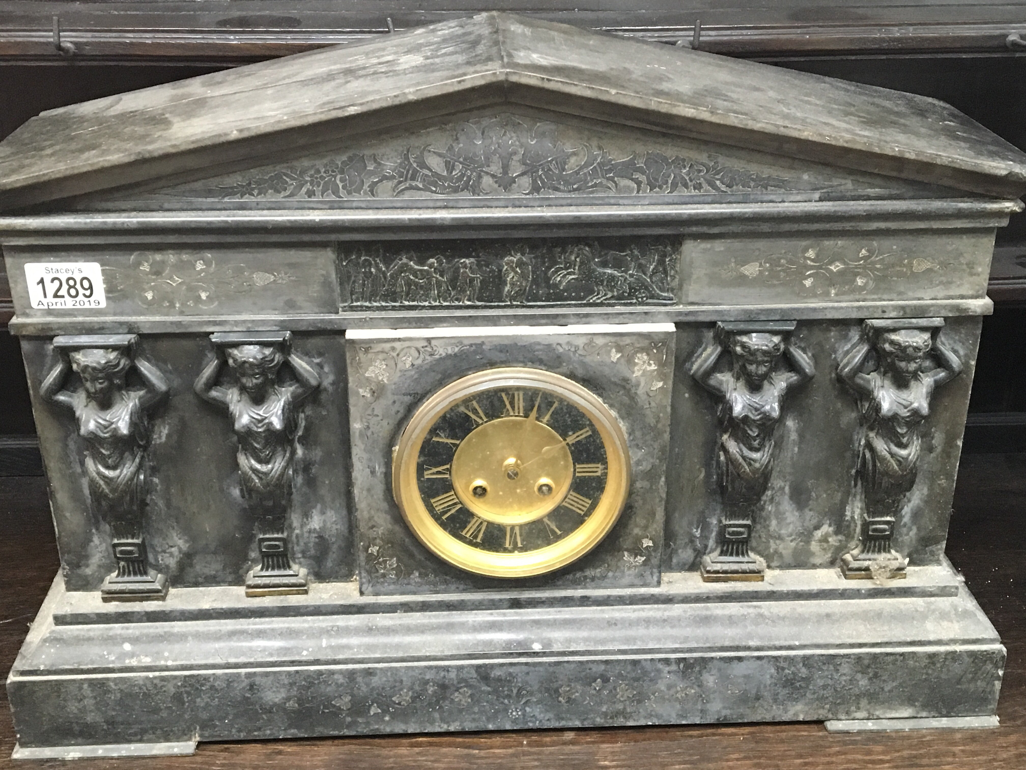 A large black slate mantle clock with raised appli