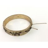 A 9ct gold bangle decorated in relief with stone s