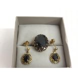 A gold garnet set ring and conforming drop earring