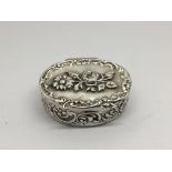 A Silver box decorated with flowers and of oval sh