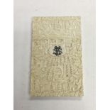 A late Victorian ivory card case with carved decoration of figures in a garden setting.