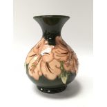A petite green Moorcroft vase decorated with Hibiscus flowers. Measures approx 13cm tall.