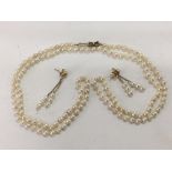 A sea pearl necklace and a pair of pearl earrings with gold clasps.