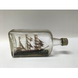 A small sailing ship in a glass bottle with faux ocean scene. Boat length approx 12cm.