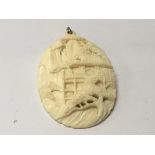 A carved early 20th Century ivory pendent/brooch in the form of a pagoda with rocks and foliage. 6.