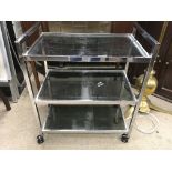 A chrome and tinted glass drinks trolley of retro design. Measures approx 61cm x 36xm x 71cm.