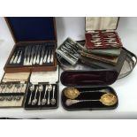 A collection of silver plated cutlery sets including a cased pair of large berry spoons, mother of