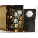 A tin containing a folding travel clock and a collection of various watches.