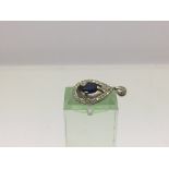 A white gold pendant marked 10k set with a central sapphire and surrounded by small diamonds, approx