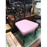 A pair of Edwardian chairs with carved backs and pink upholstered seats.