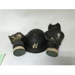 A WW2 military helmet alongside two gas masks, one dated 1938.