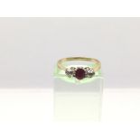 A gold ring set with a central ruby and two diamonds, approx 1.9g and approx size L.