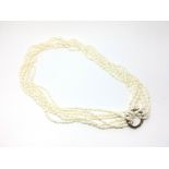 A Japanese cultured pearl necklace comprised of three folded strands mounted on a white metal hoop.