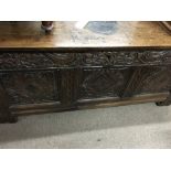 An oak 18th century blanket box the hinged lid above a three carved panel front 146 by 55 cm